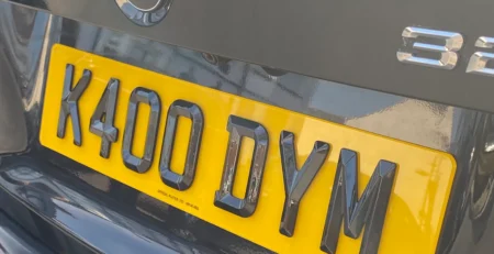 Rear yellow number plate reading K400 DYM, in 4D retro style, on blue BMW