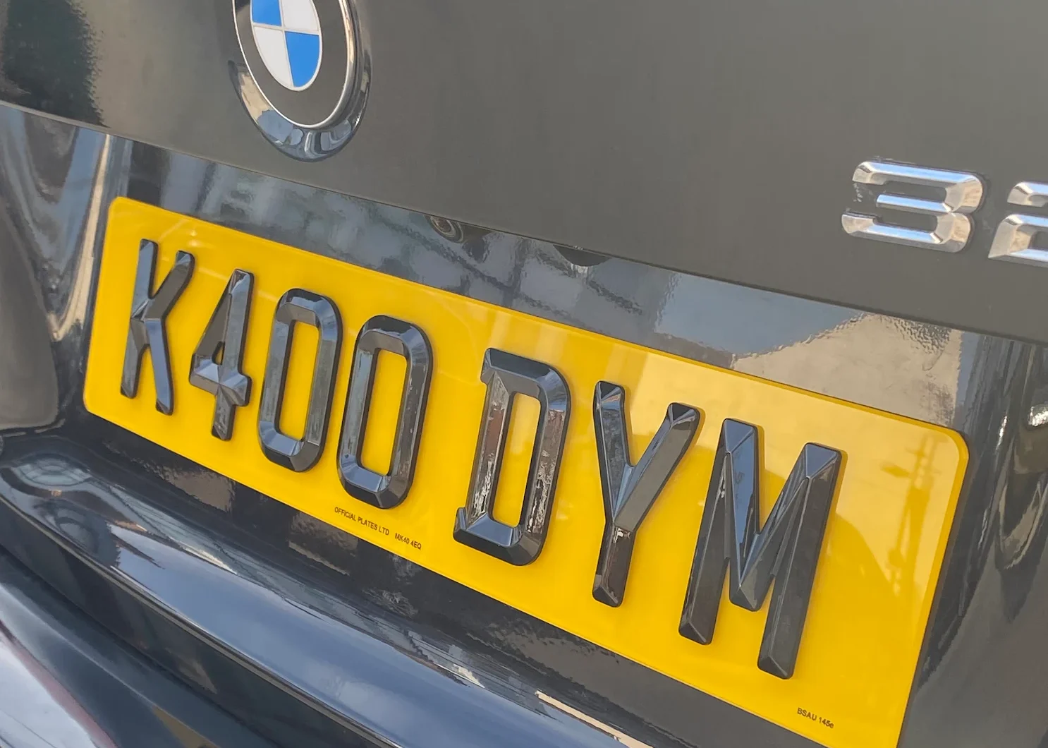 Rear yellow number plate reading K400 DYM, in 4D retro style, on blue BMW